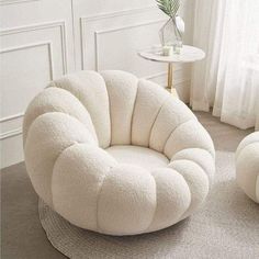 a white chair and ottoman on a rug in a living room with a potted plant