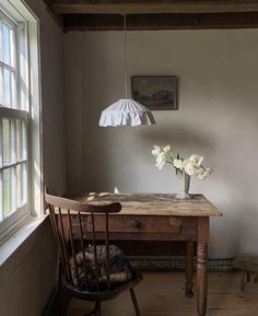 a room with a table, chair and lamp on the floor next to a window