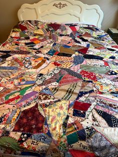 an old quilt is laying on top of a bed with white headboard and foot board