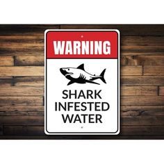 a warning sign on a wooden wall that says shark infested water