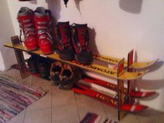 there are many pairs of skis and boots on the shelf