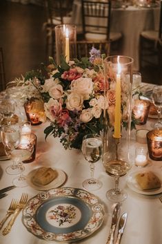 the centerpieces on this table are filled with flowers, candles and wine glasses