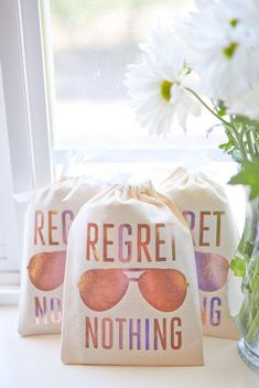 two bags sitting next to each other on a window sill with flowers in front of them