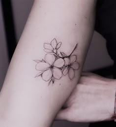 a woman's arm with a small flower tattoo on the left side of her arm