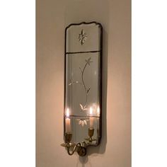 a wall mounted mirror with two candles on it