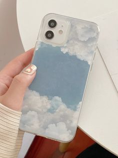 a person holding an iphone case with clouds in the sky