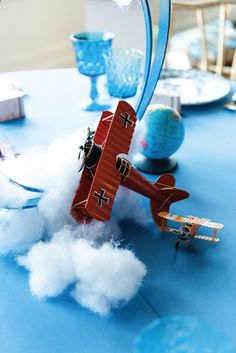 a toy airplane is flying through the air on a table with clouds and blue plates