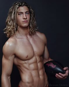 a man with long hair and no shirt holding a football