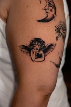 a woman's arm with tattoos on it and an angel sitting in the middle