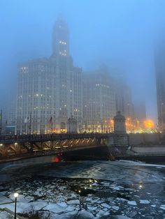 foggy night in the city with skyscrapers and bridge over frozen water at dusk