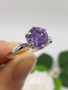 a person holding a ring with a purple stone in it