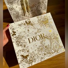 the dior book is being held up by someone's hand with scissors in it