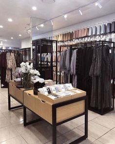 a clothing store with clothes on racks and tables in front of the display cases,