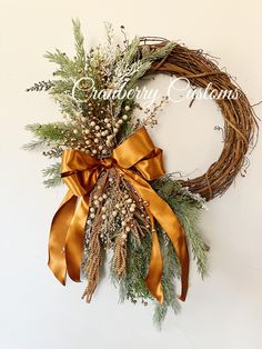 a wreath with gold ribbon and pine cones