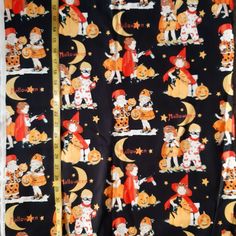 a halloween themed fabric with cats and pumpkins on it, as well as a measuring tape