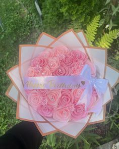 a bouquet of pink roses with a happy birthday ribbon on it in someone's hand