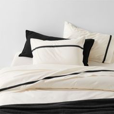 a bed with black and white sheets and pillows