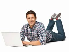 a young man laying on the floor with his feet up while using a laptop computer