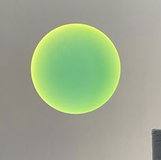 a large round object in the middle of a gray and white sky with a light green circle above it