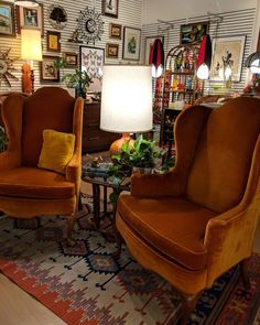 two orange chairs sitting on top of a rug in a living room next to a lamp