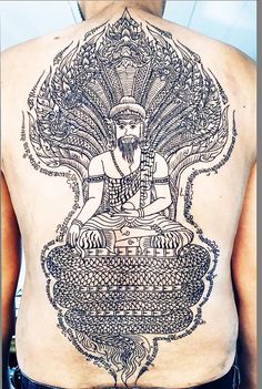 the back of a man's body with an intricate tattoo design on his chest