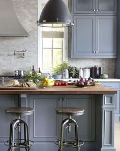 two stools are in front of the kitchen island with fruit and vegetables on it