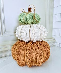 three crocheted pumpkins are stacked on top of each other in different colors