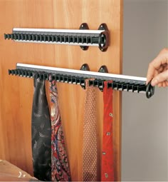 the tie rack is holding two ties on it's side, while someone holds them in their other hand