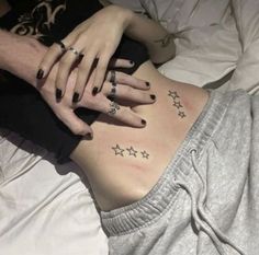 a woman laying on top of a bed with her stomach covered in stars and rings