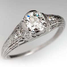 an antique style diamond ring with filigrees on the band and center stone