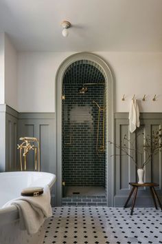 a white bath tub sitting under a window next to a tiled floor covered in black and white tiles