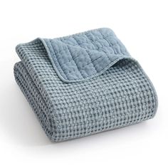 a blue blanket folded on top of a white surface with a black and white checkered pattern