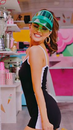 a woman in a black and white dress is holding a banana while wearing a green visor