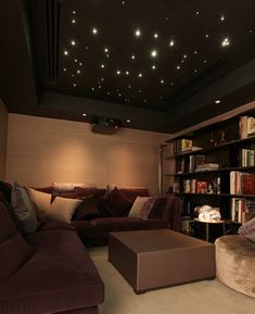 a living room filled with lots of furniture and bookshelves under a ceiling covered in stars