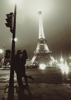 a couple kissing in front of the eiffel tower at night with lights on