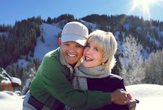 a man and woman hugging each other in the snow