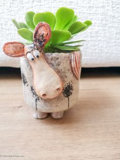 a ceramic cow planter sitting on top of a wooden table