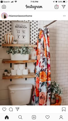 a bathroom with toilet, shower curtain and shelves filled with plants on the wall next to it