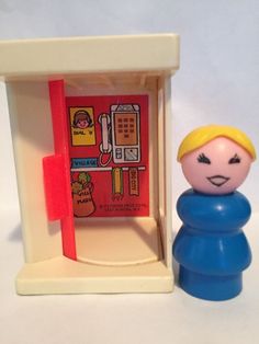 a small toy figure next to a dollhouse with a phone booth on the wall