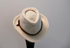 a white crocheted hat sitting on top of a wooden stand