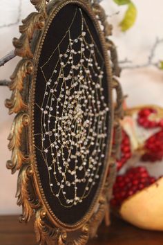 an ornate gold frame with beaded details on it and pomegranates in the background