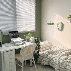 a bedroom with a bed, desk and computer on the wall next to window blinds