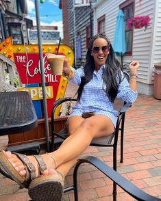 a woman sitting in a chair with her feet up and holding a cup of coffee