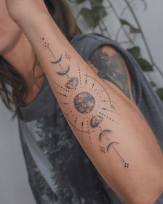 a man with a tattoo on his arm pointing at the sun and stars in the sky