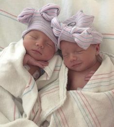 two newborn babies wrapped in blankets on top of each other