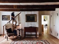 a living room filled with furniture and a stair case next to a painting on the wall