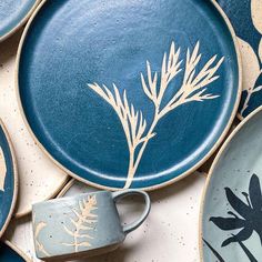 blue plates with white designs on them and a coffee cup in the middle one is surrounded by other plates