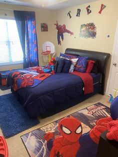 a spiderman themed bedroom with blue and red bedding, rugs and curtains