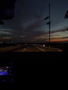 the dashboard of a car at night with lights on and dark clouds in the sky