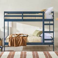 a blue bunk bed sitting in a bedroom next to a rug and wall mounted lamp